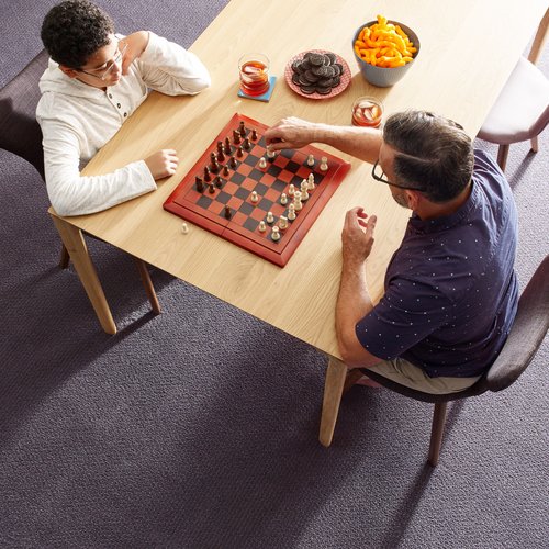 child and son playing chess on wooden table