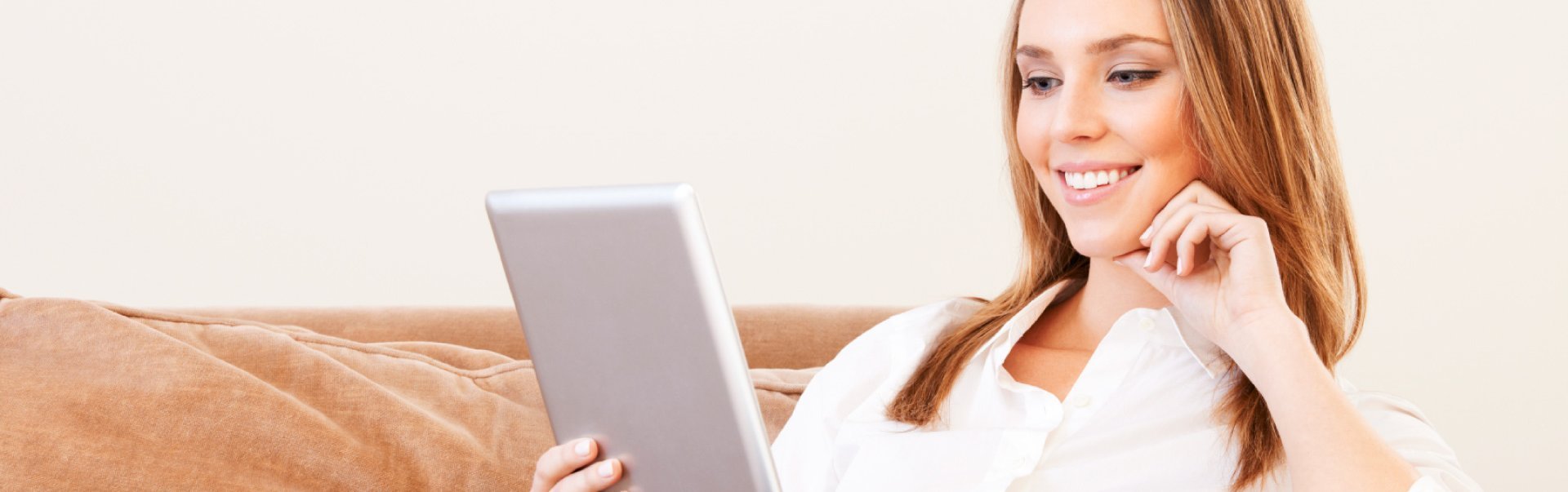 woman holding tablet while sitting on couch