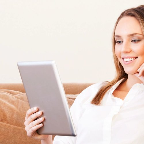 woman sitting on couch with tablet in hand